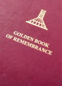 Maroon leatherette cover embossed in gold with a stylised monument emblem above the title GOLDEN BOOK OF REMEMBRANCE.